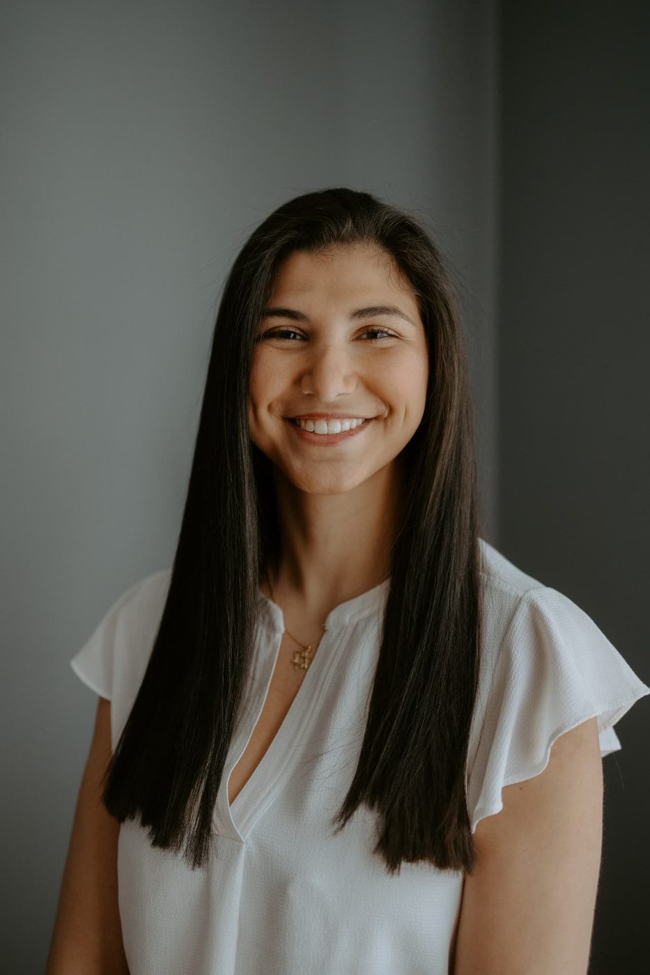 Studio portrait of Reilly Biller Kinzel smiling in a white blouse